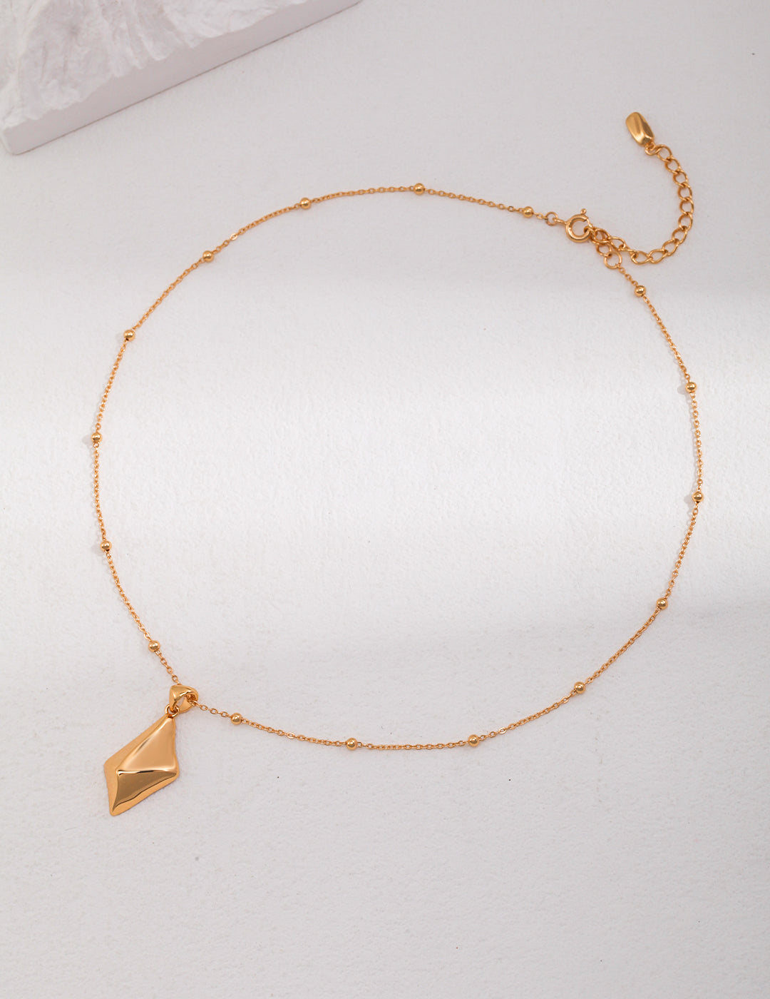 Elegant gold necklace featuring a dainty triangle pendant with rhombus star detail.