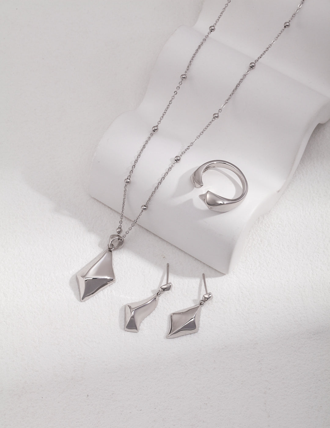 A set of silver jewelry including a rhombus star pendant necklace, earrings, and a ring.