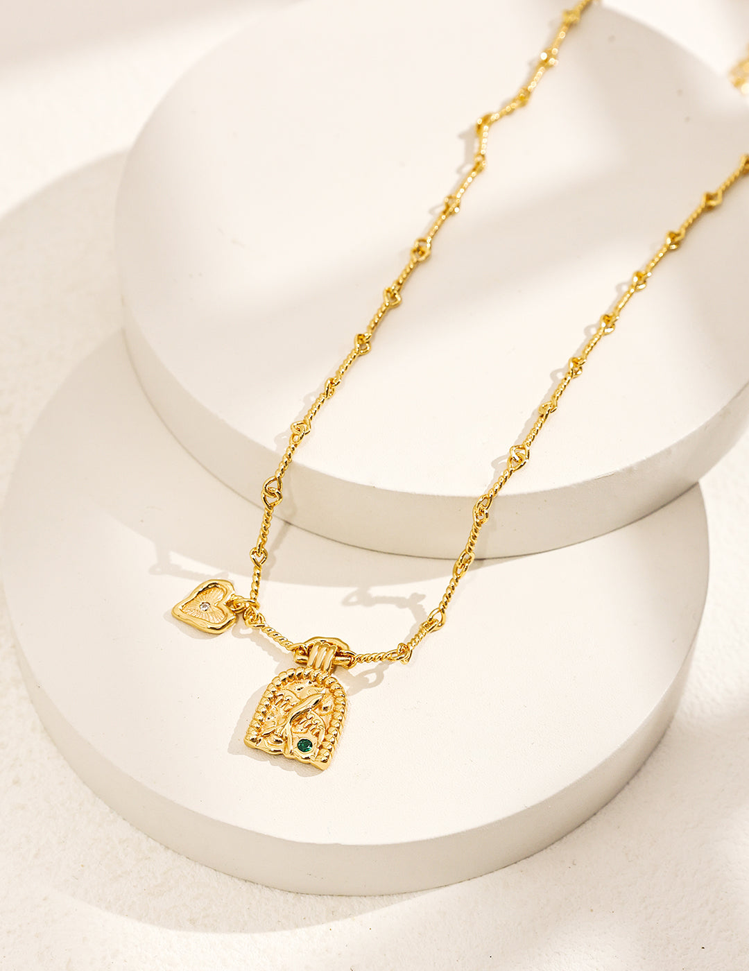 Stylish gold chain necklace featuring heart charm and a bird engraved charm.