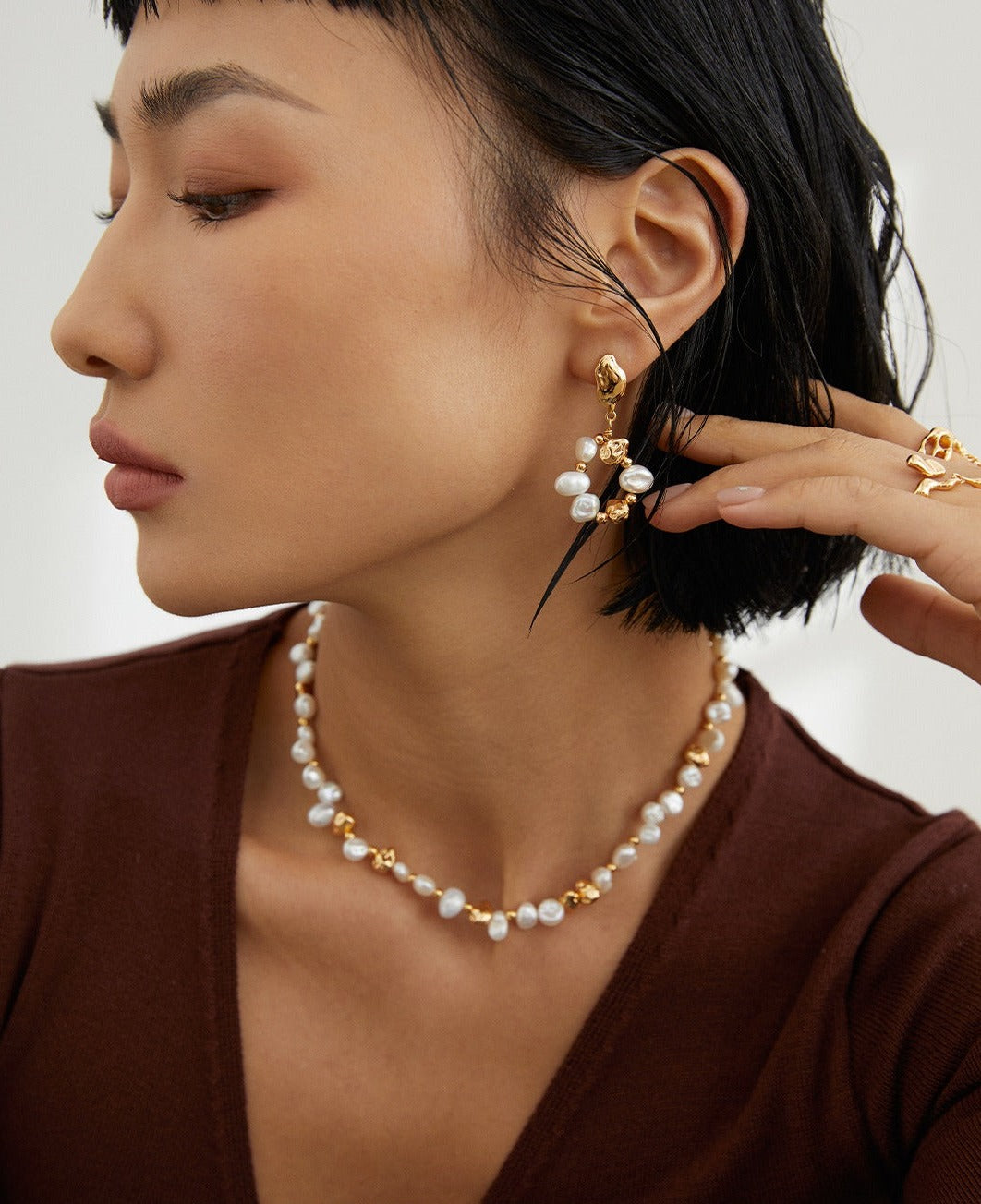 Stylish model showcasing gold necklace and freshwater pearl earrings.