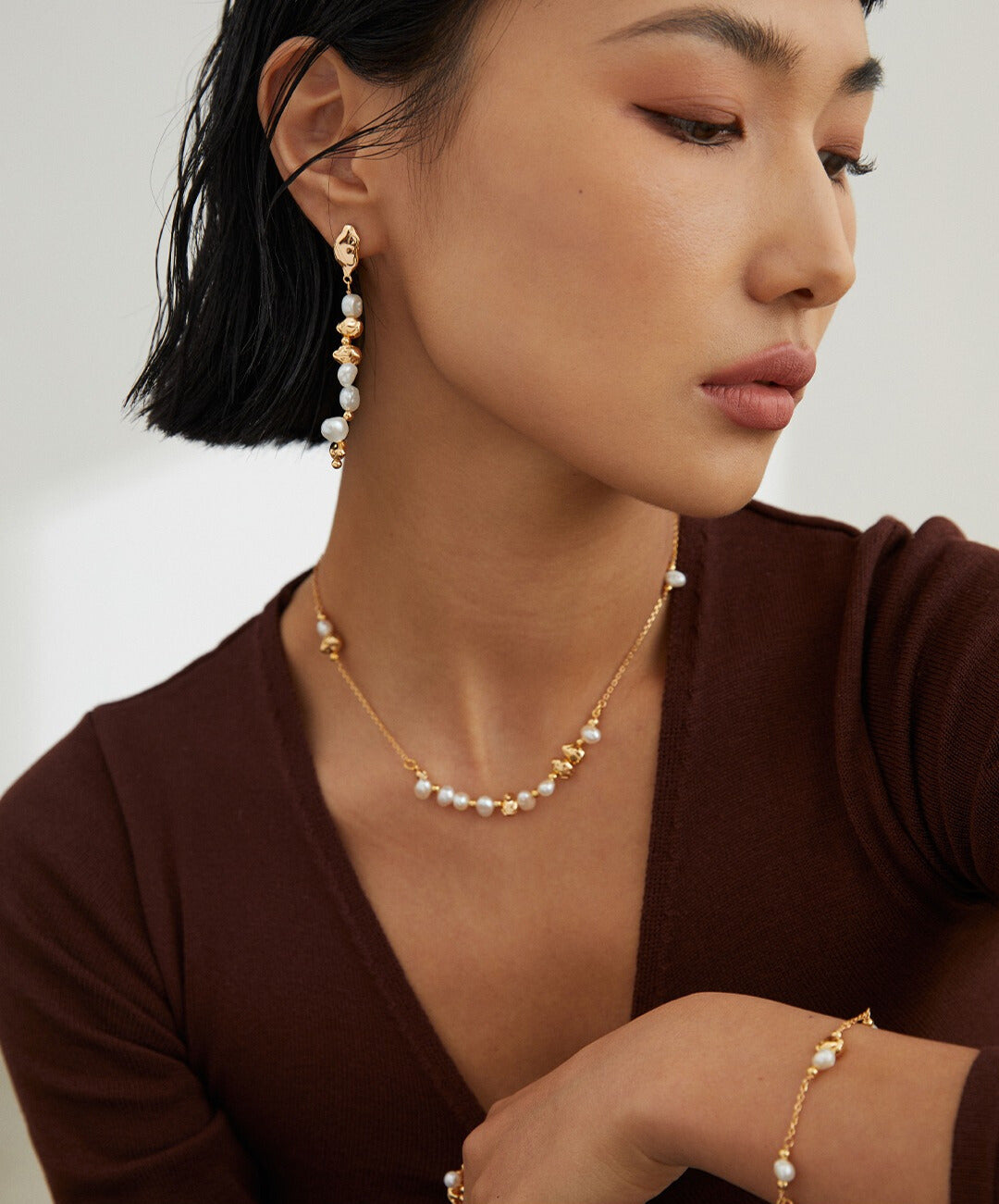 Elegant lady adorned in gold plated pearl necklace and earrings.