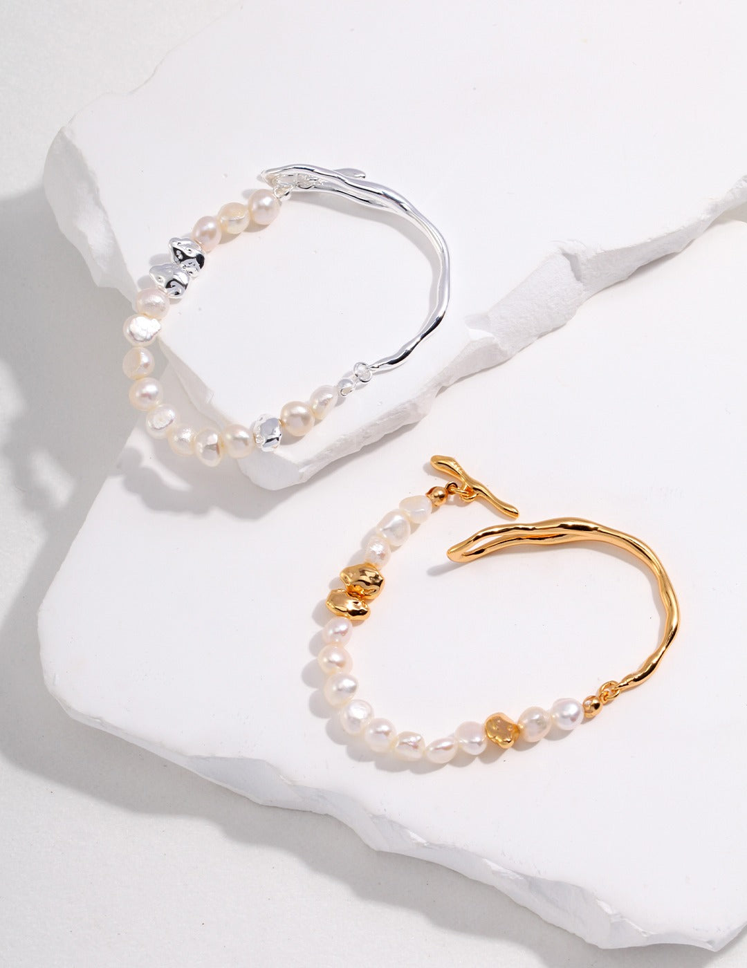 Two elegant bracelets adorned with pearls, one gold and one silver.