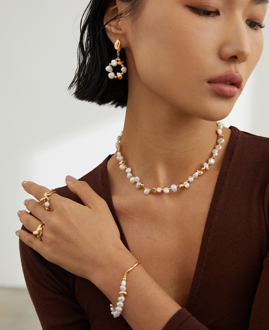 Model wearing a pearl necklace and earrings, exuding elegance and sophistication.