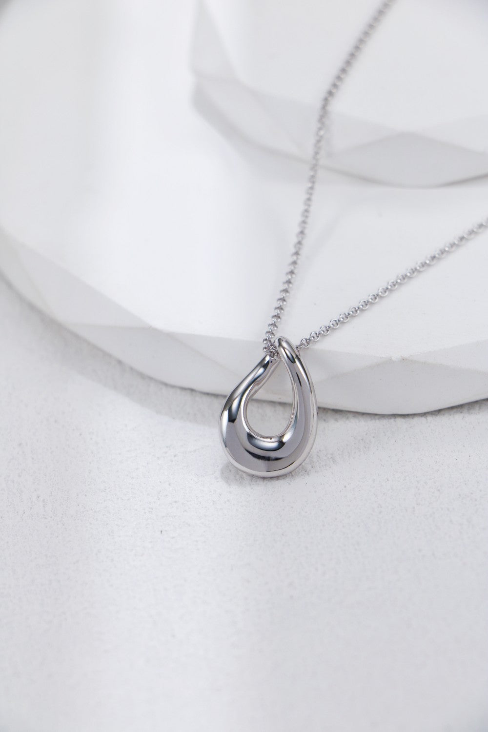 A silver circular pendant displayed on a white background, highlighting its beauty as a necklace accessory.