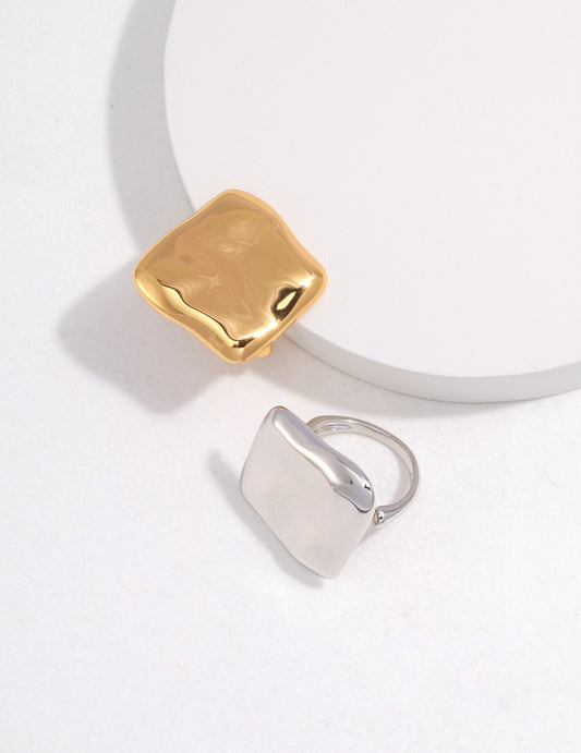 Two square rings, one gold and one silver, placed on a white surface.