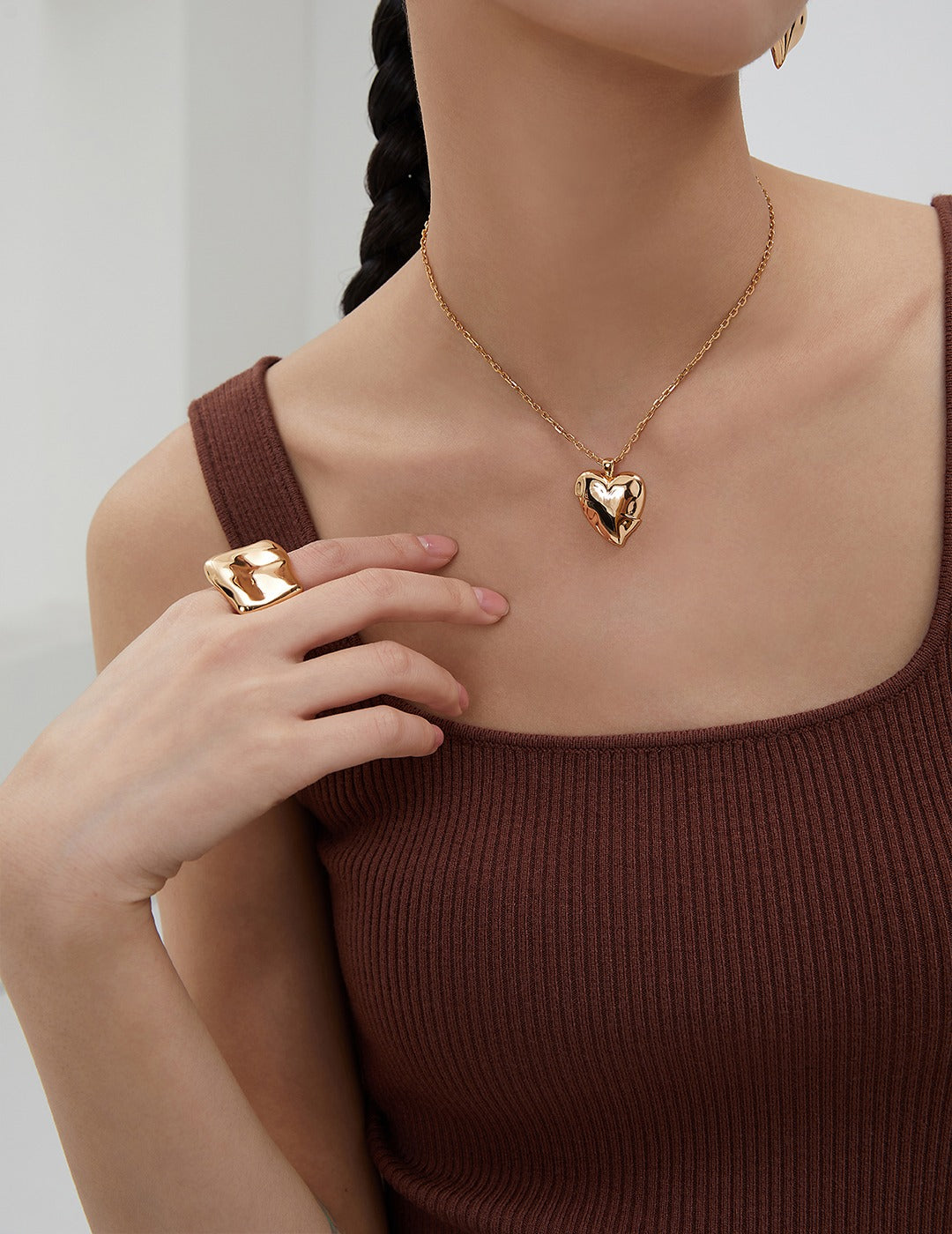 Woman showcasing gold squary ring and matching jewelry.