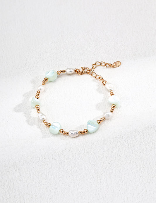 Elegant bracelet made of green and white beads, adorned with freeform shells and freshwater pearls for a stylish look.