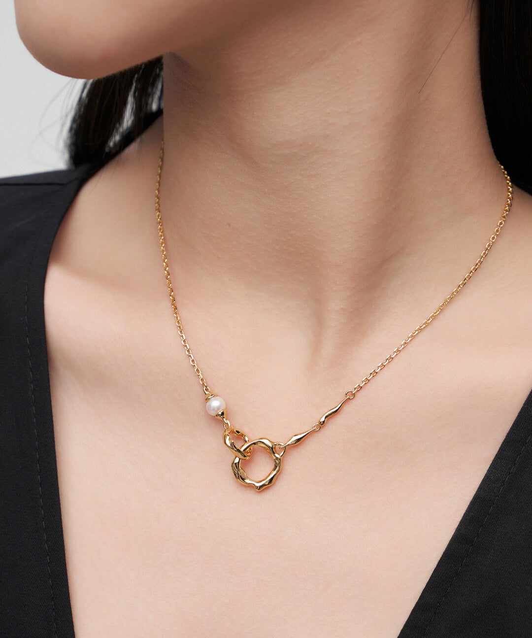 Model showcases gold necklace adorned with double rings interlocked and freshwater pearl.