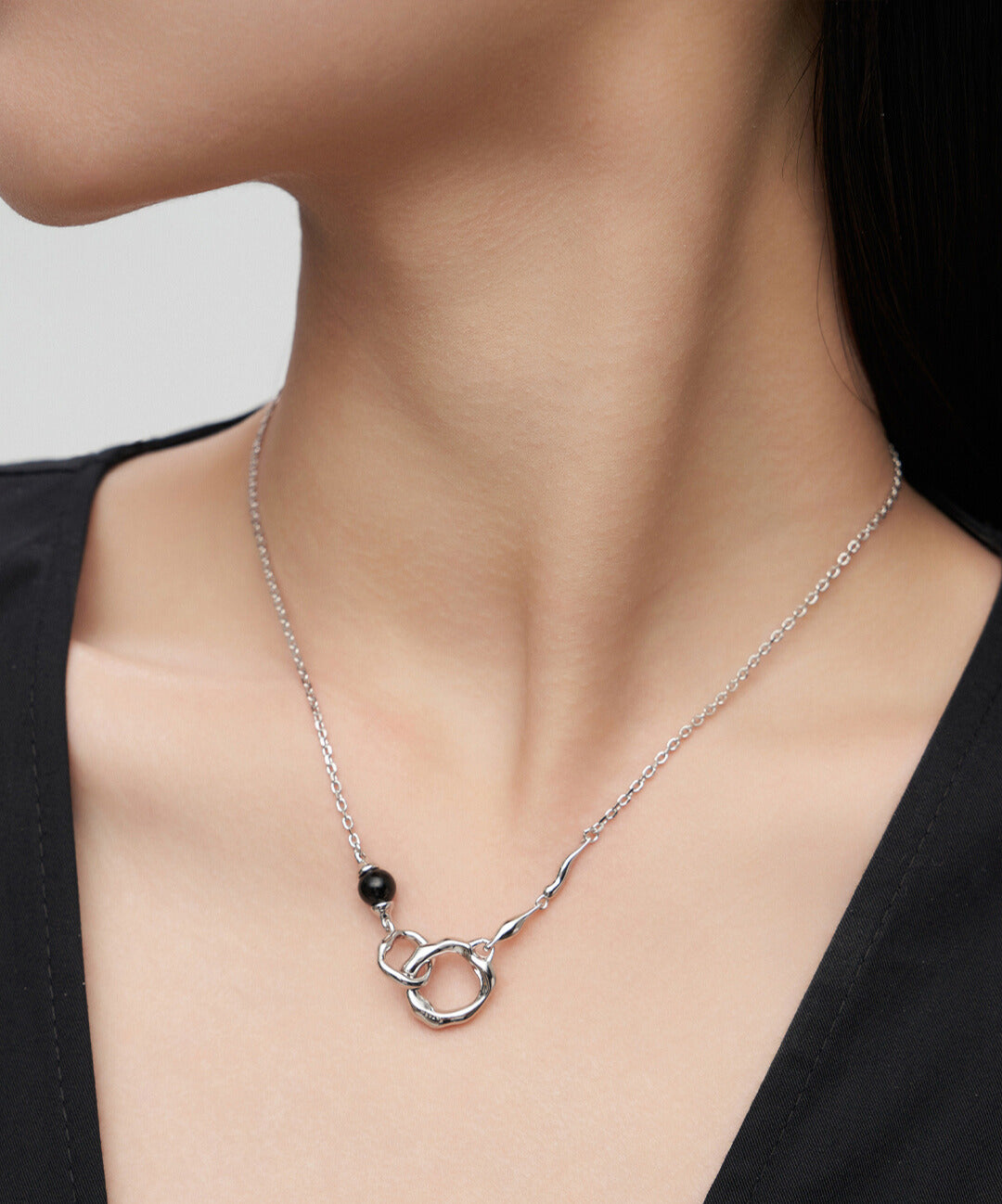 Woman wearing silver double rings interlocked necklace with black agate.