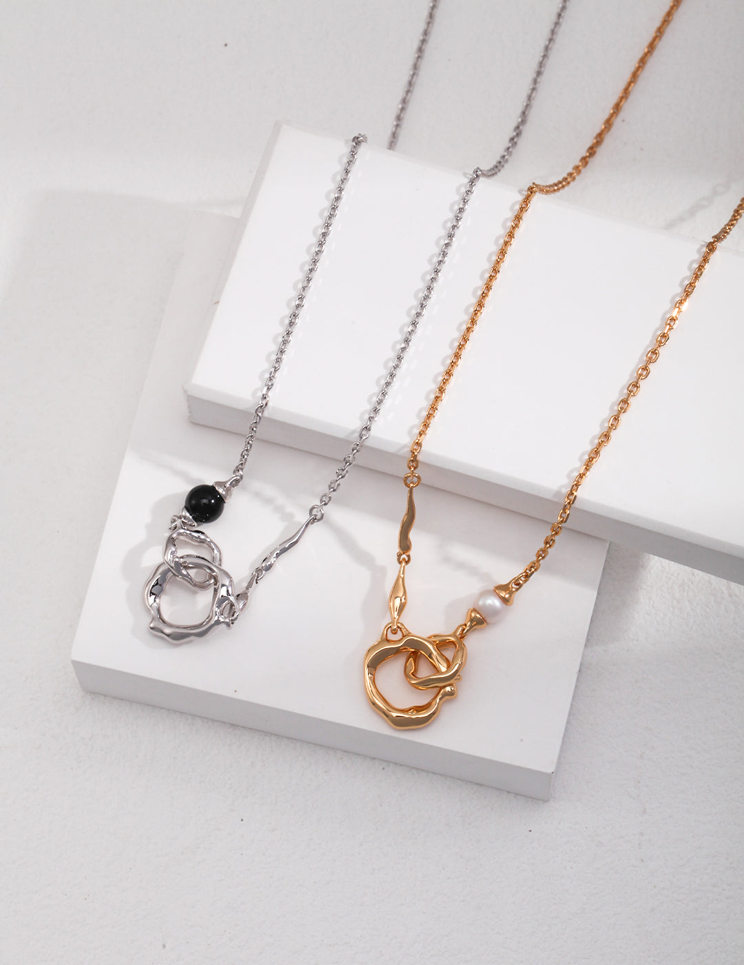 Two double rings interlocked necklaces in silver and gold.