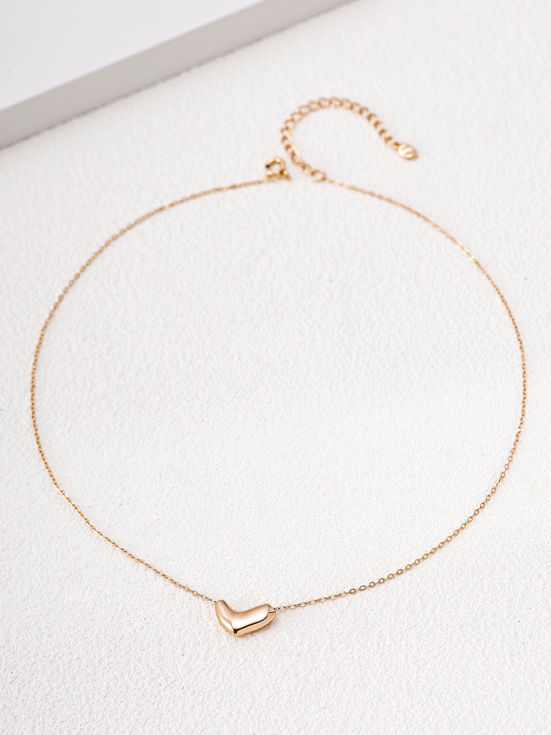 Flat lay of the gold Mezuille Beanie Necklace featuring an adjustable chain and minimalist pendant.