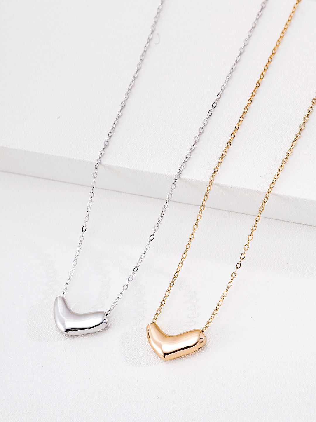 Side-by-side display of the silver and gold Mezuille Beanie Necklace featuring smooth bean pendants.