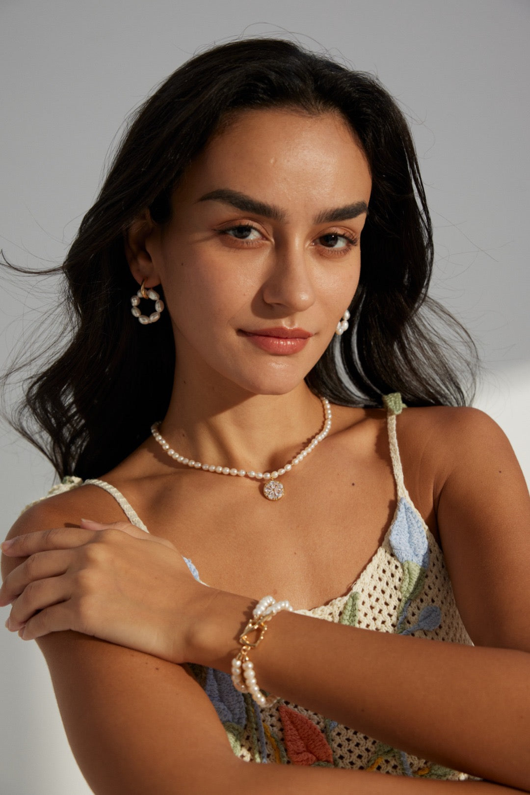 Woman wearing pearl necklace and earrings from Mezuille under sunlight.