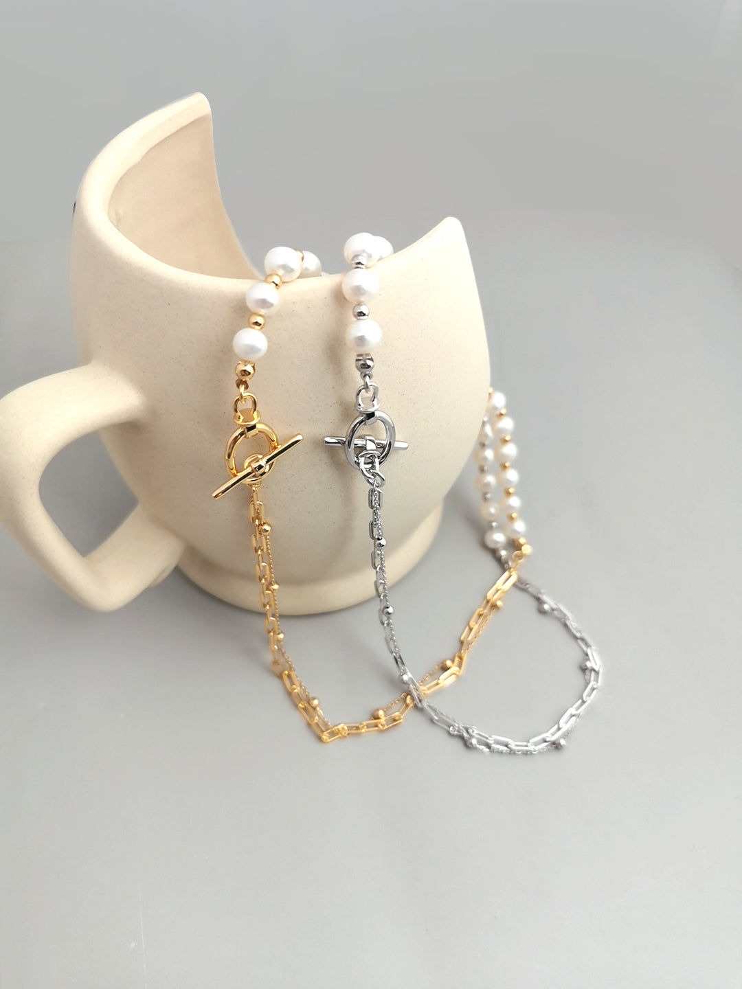 Elegant white cup adorned with chained & pearl necklace, showcasing two necklaces with half pearls & half chain in silver & gold.