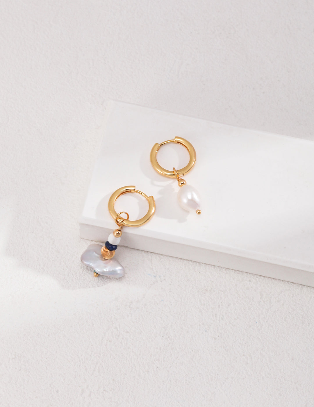 Gold hoop earrings with pearls and a small stone, featuring a playful mix of elegance and charm.