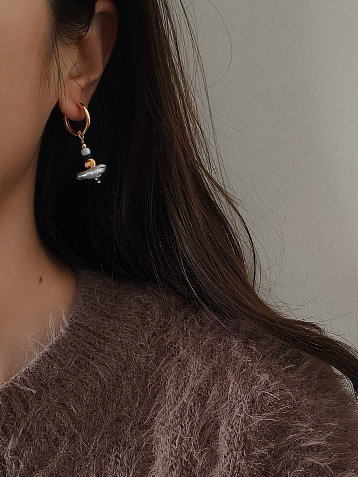 Female in sweater and playful gold hoop earrings.