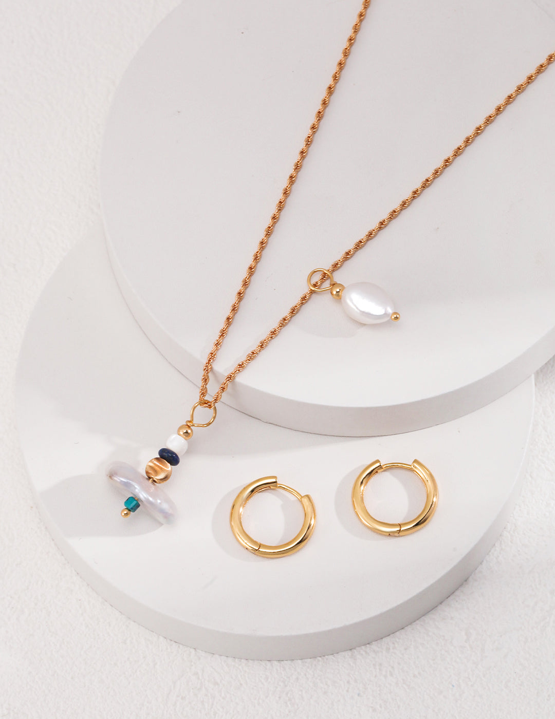 Stylish gold necklace adorned with pearl and two earrings, complete with gold hoops, can be worn as a necklace.