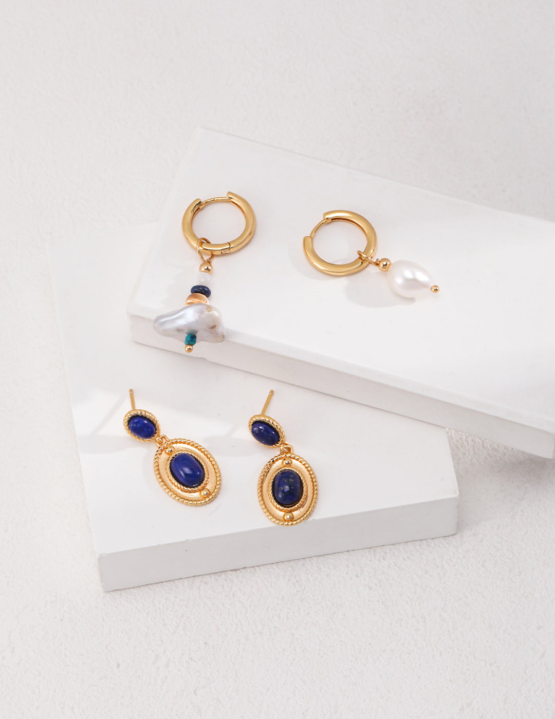 Gold hoops with blue stones and pearls, creating a playful mix with other earrings.