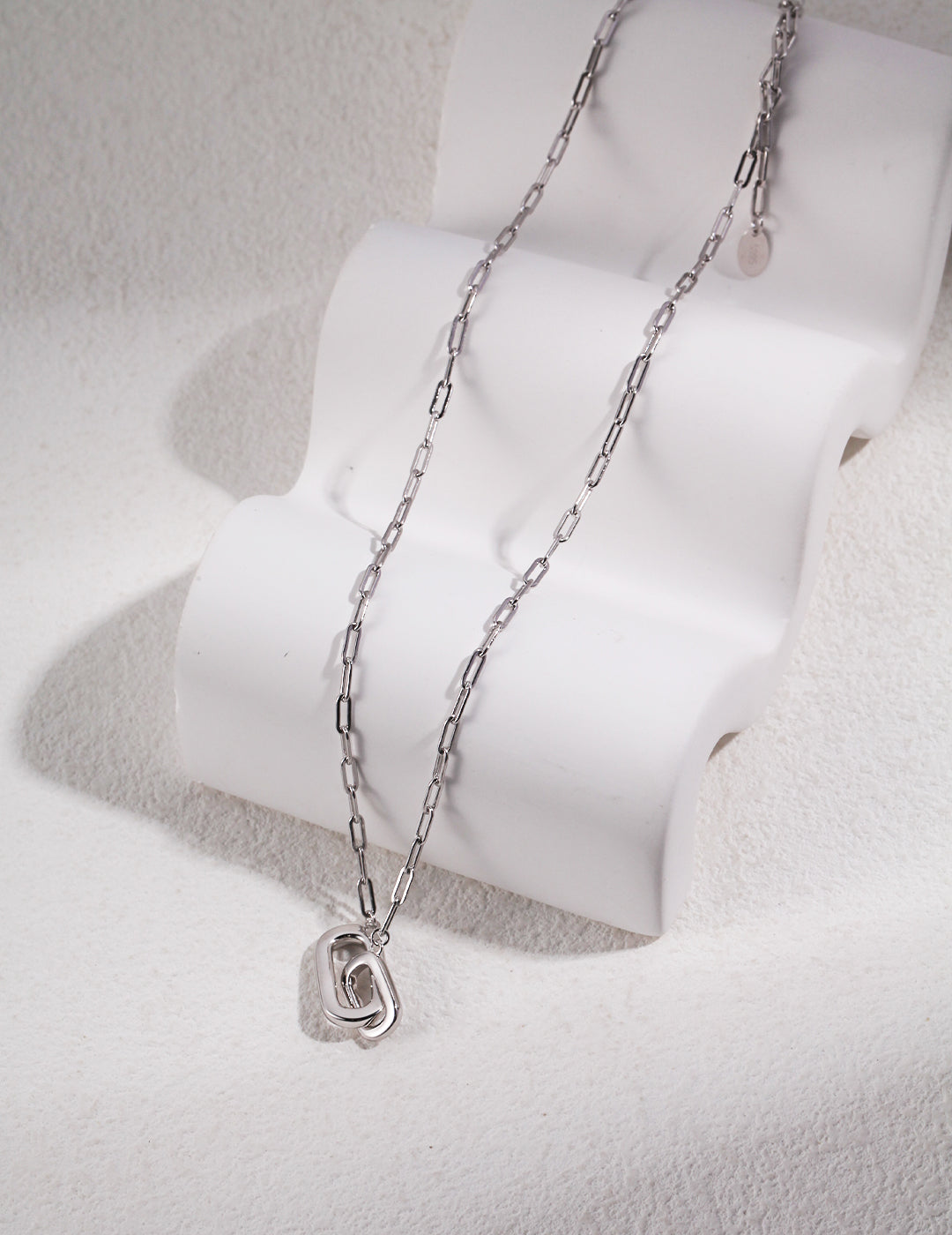 A gold chain necklace with a silver interlocking ring pendant.