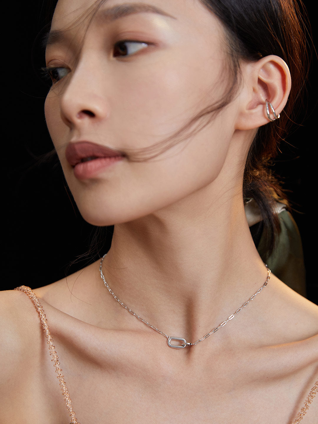 A woman with a silver chain necklace and earrings.