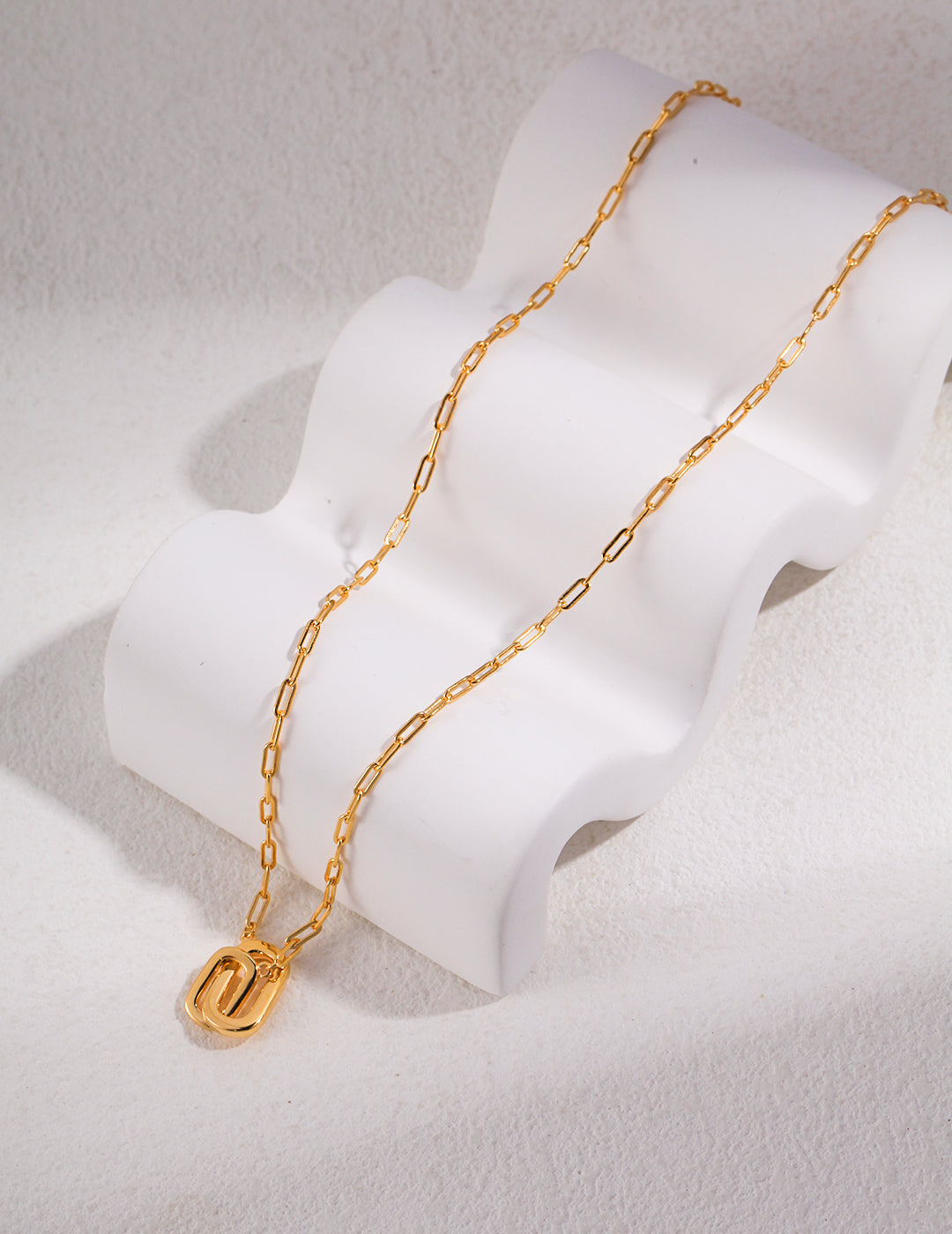 A gold chain necklace with a gold interlocking ring pendant.