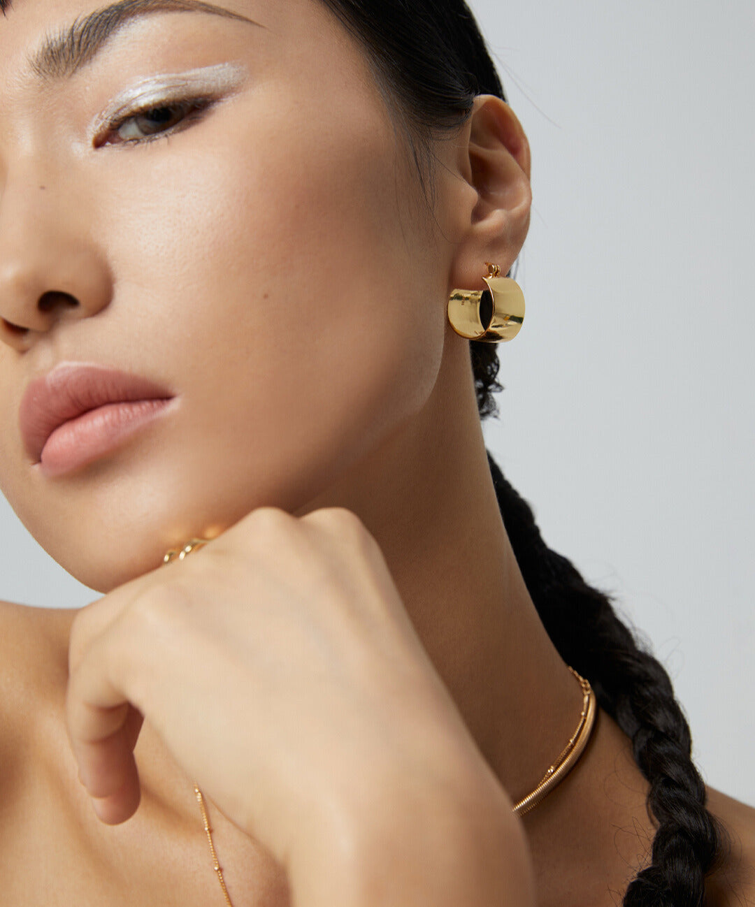 Woman with gold chunky hoops earrings and necklace