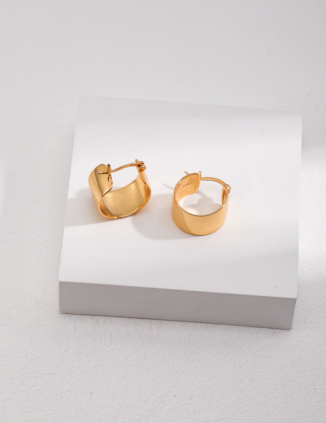 Pair of gold hoop earrings, chunky style, on white.