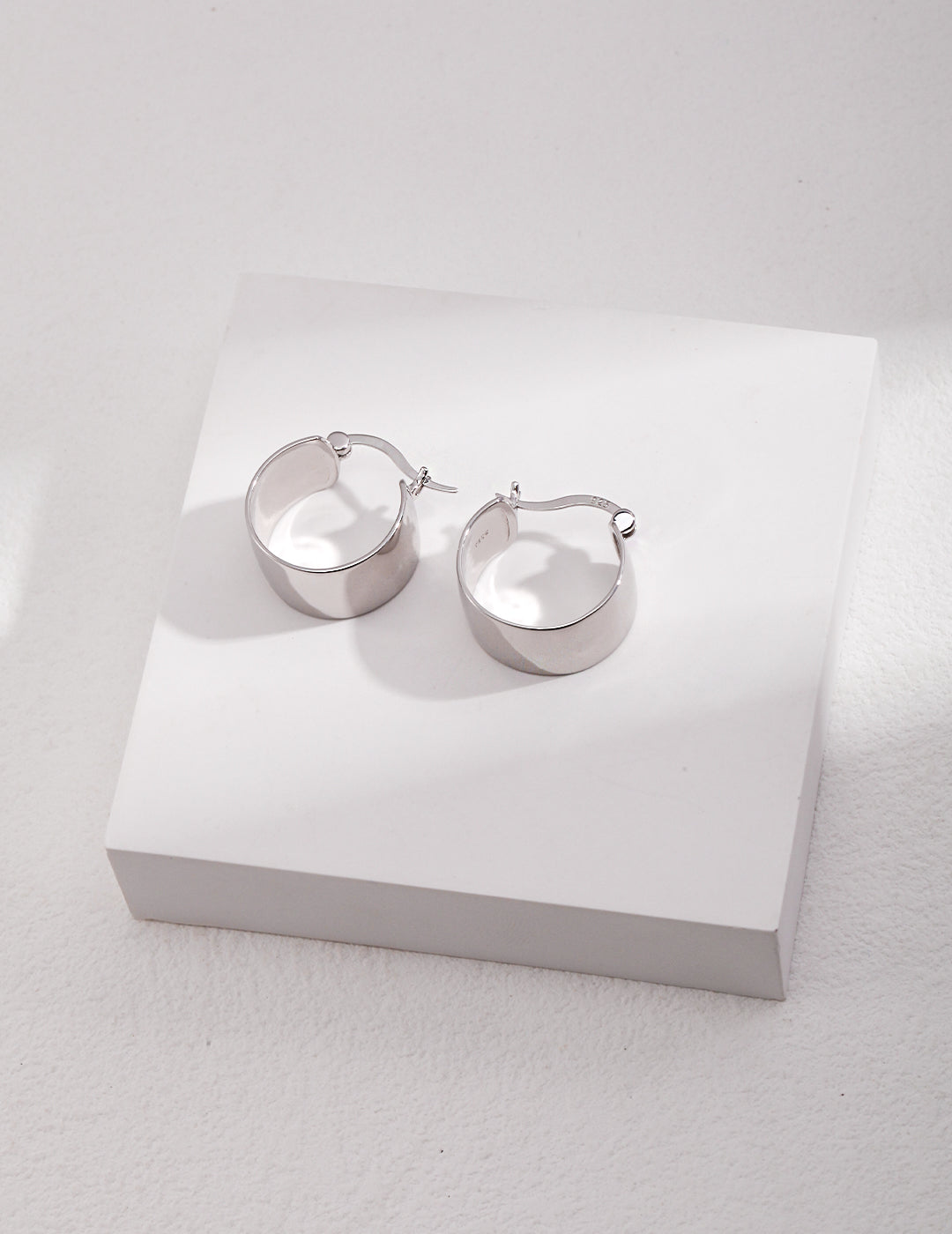 Silver chunky hoop earrings on white surface.