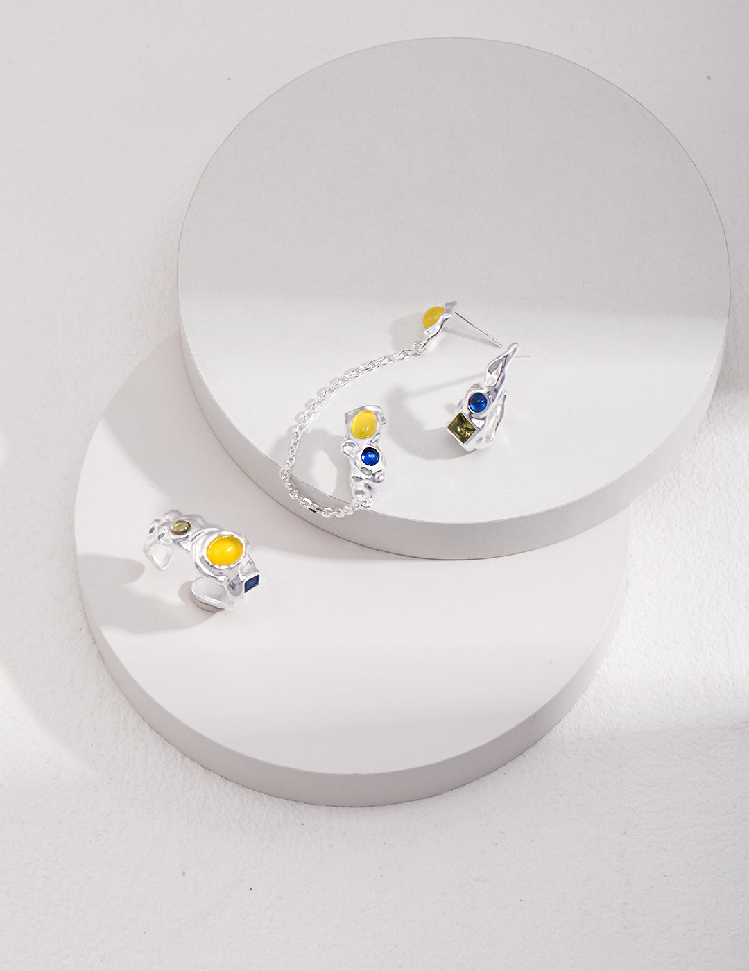 Fashionable ring adorned with yellow and blue stones, complemented by an ear cuff with vibrant cubic zirconia.