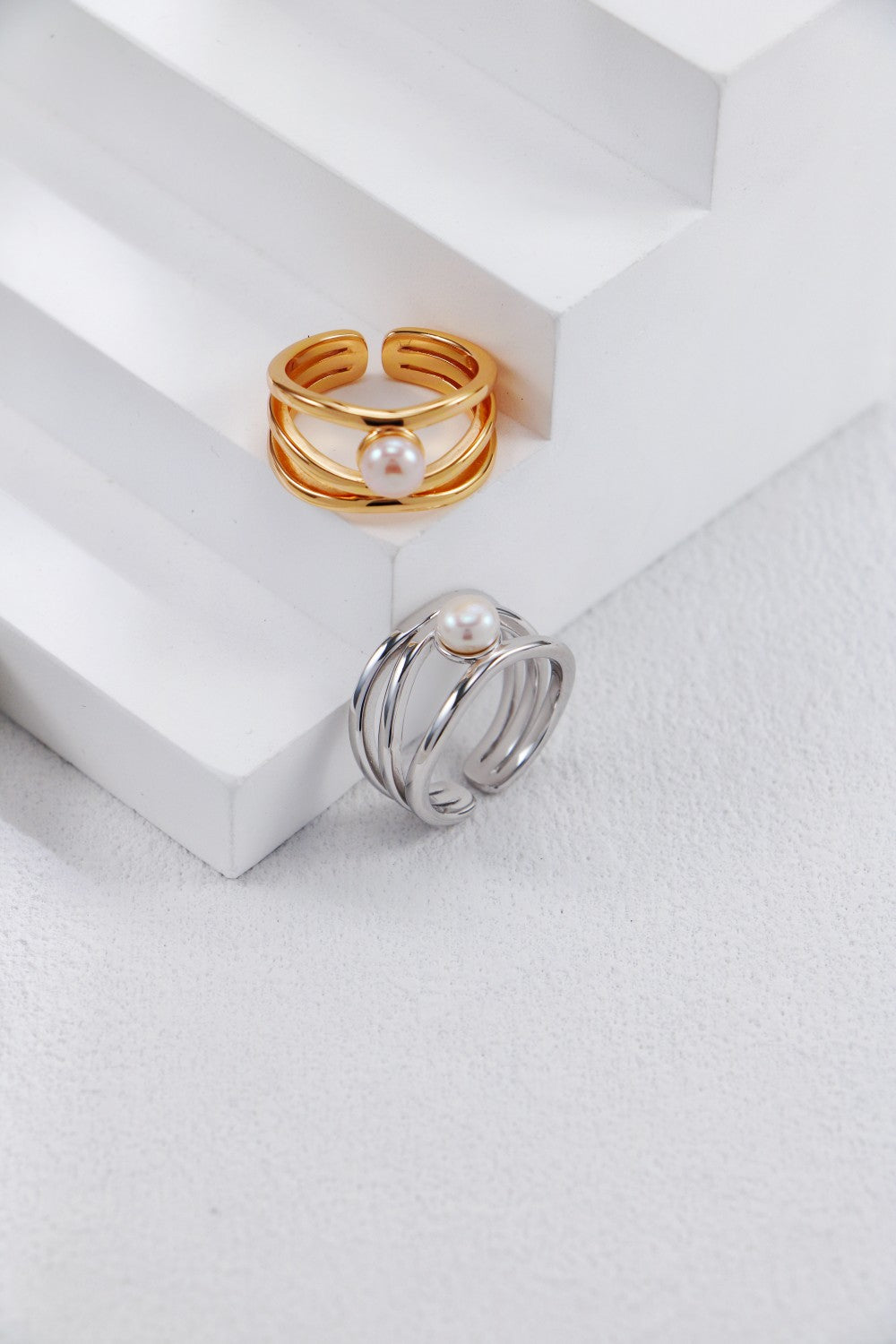 Two elegant rings available in gold and silver, featuring a lustrous pearl, showcasing a beautiful blend of colors and styles.