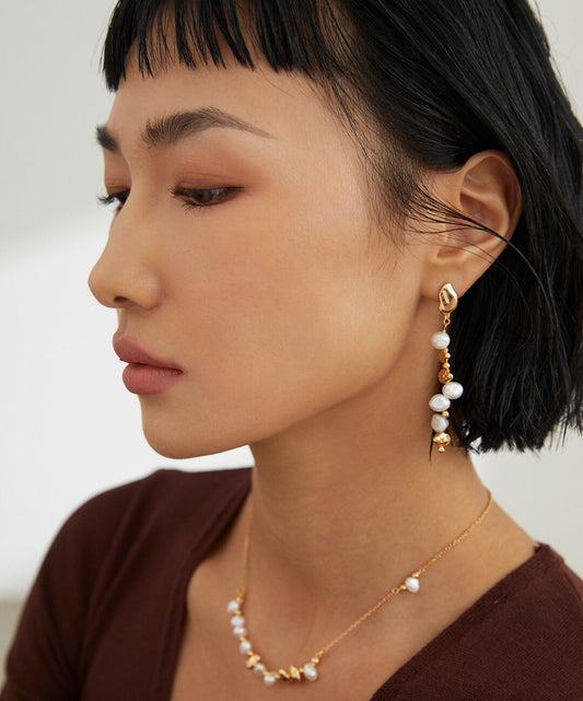 A stylish woman showcasing gold-plated baroque pearl bead earrings, adding elegance to her ensemble.