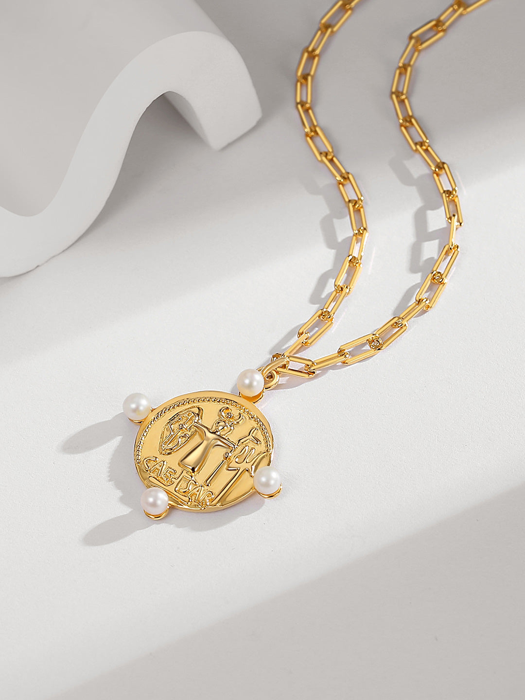 A stunning gold coin pendant necklace adorned with freshwater pearls, placed on a clean white surface.