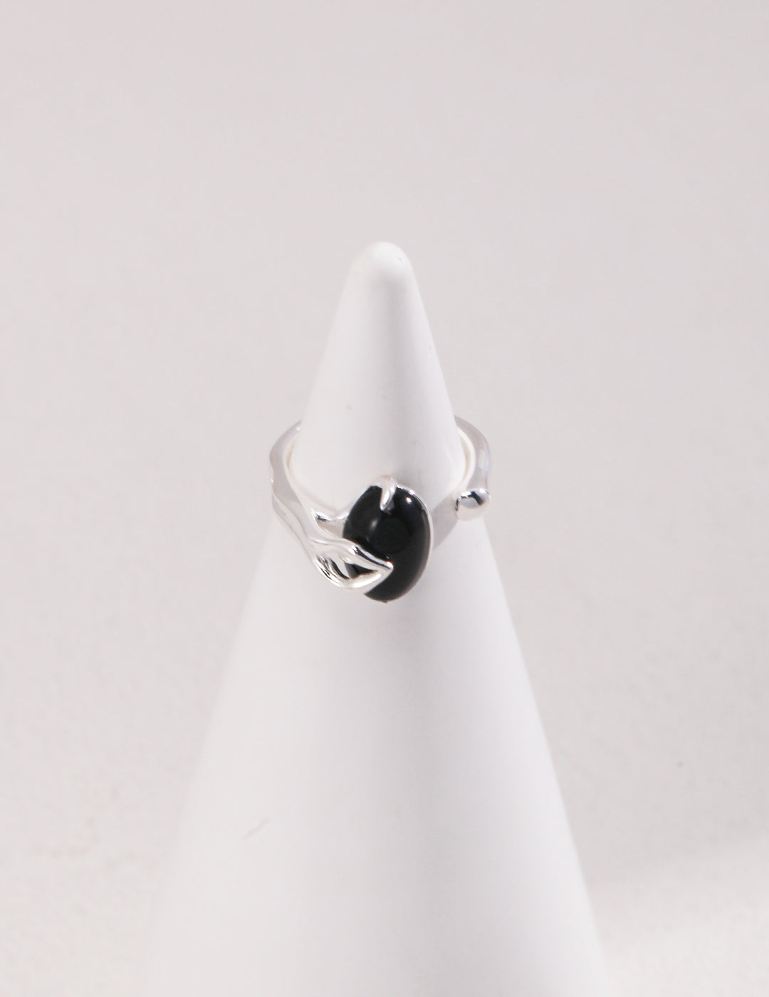 Silver ring with black agate stone on white cone.