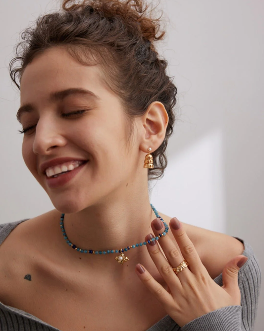 A woman adorned with an aquamarine necklace and earrings, highlighting her sophisticated and confident look.