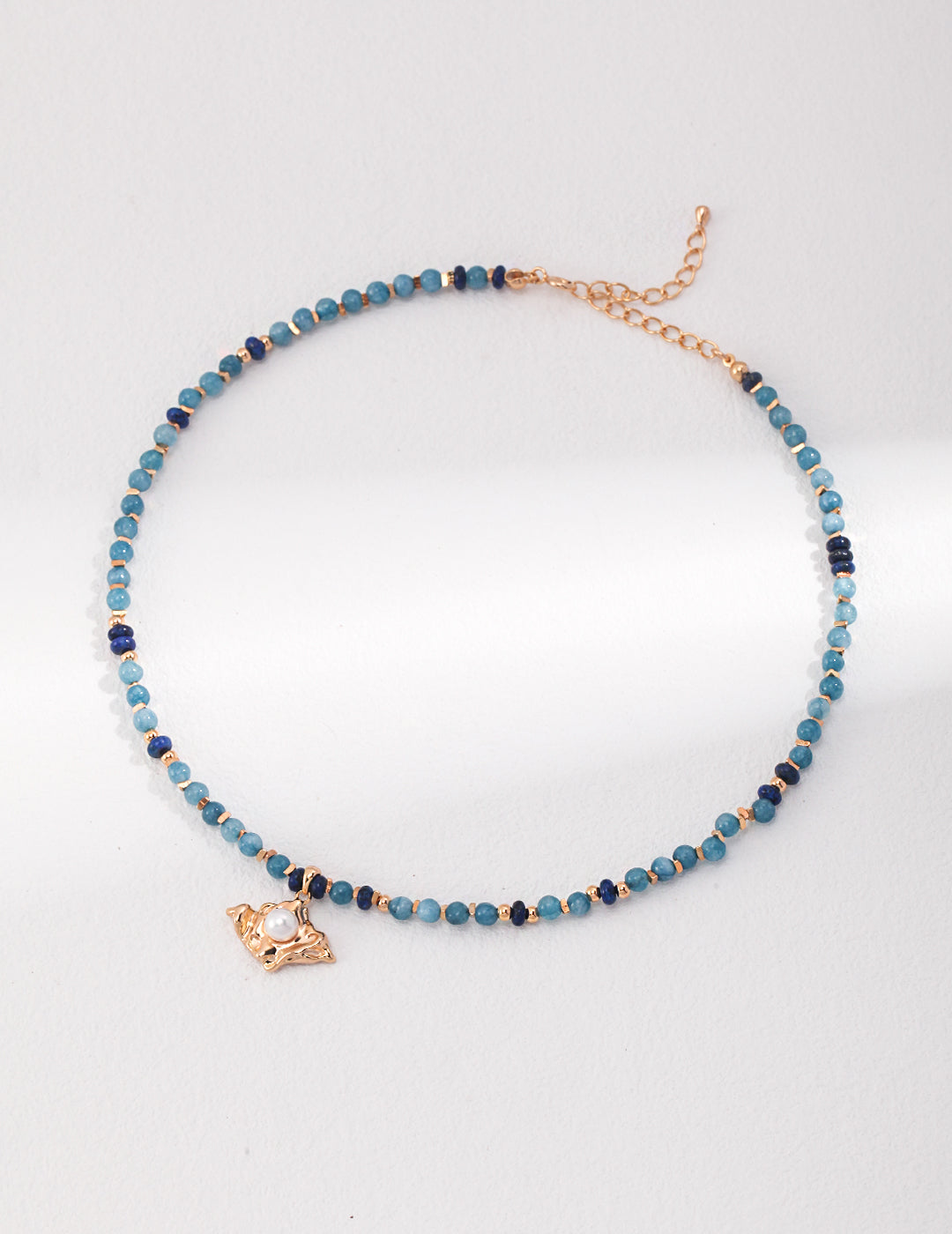 Elegant blue and gold beaded necklace with gold charm, adorned with amazonite and lapis lazuli stones.