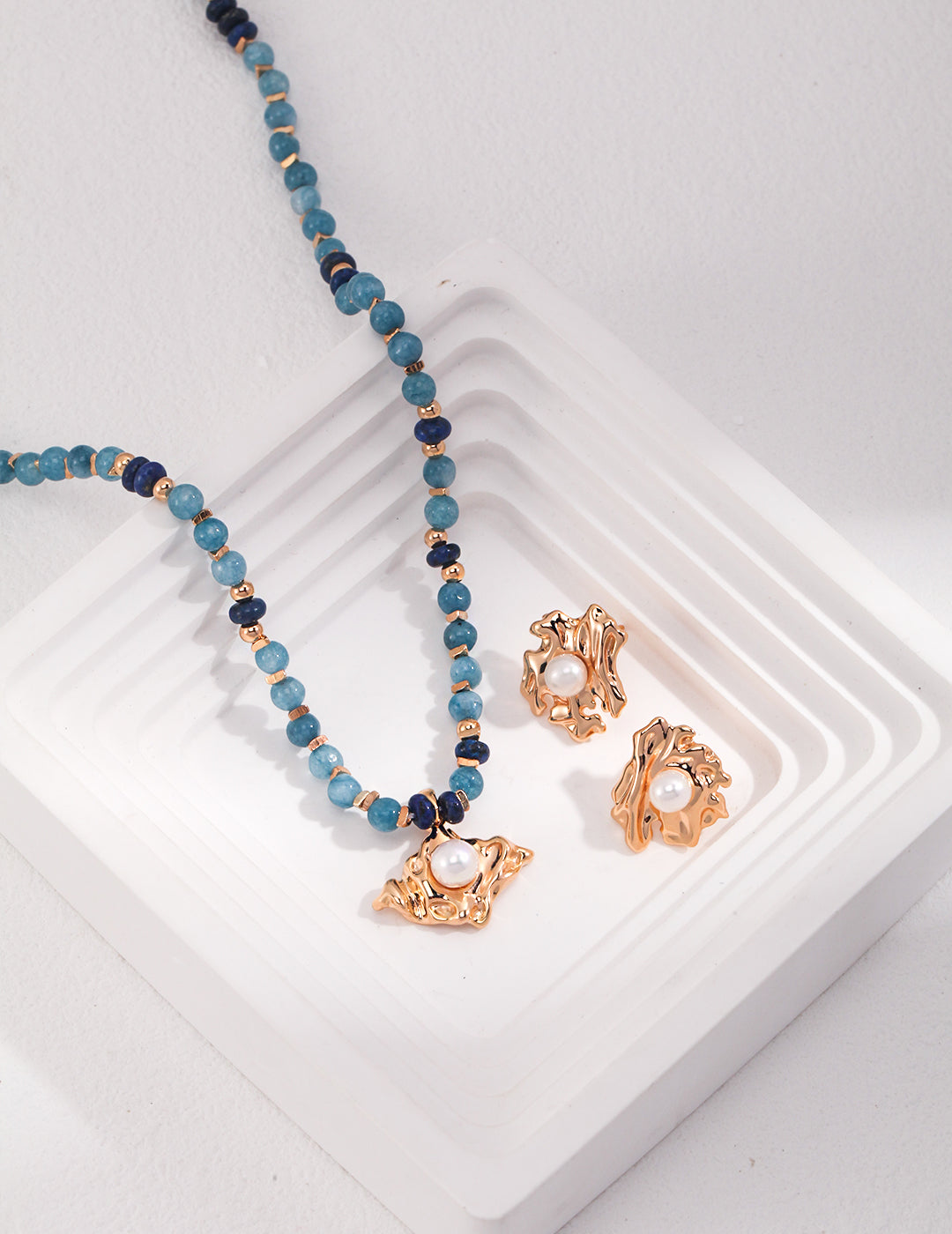 Blue amazonite and lapis lazuli necklace and earrings set on a white tray.