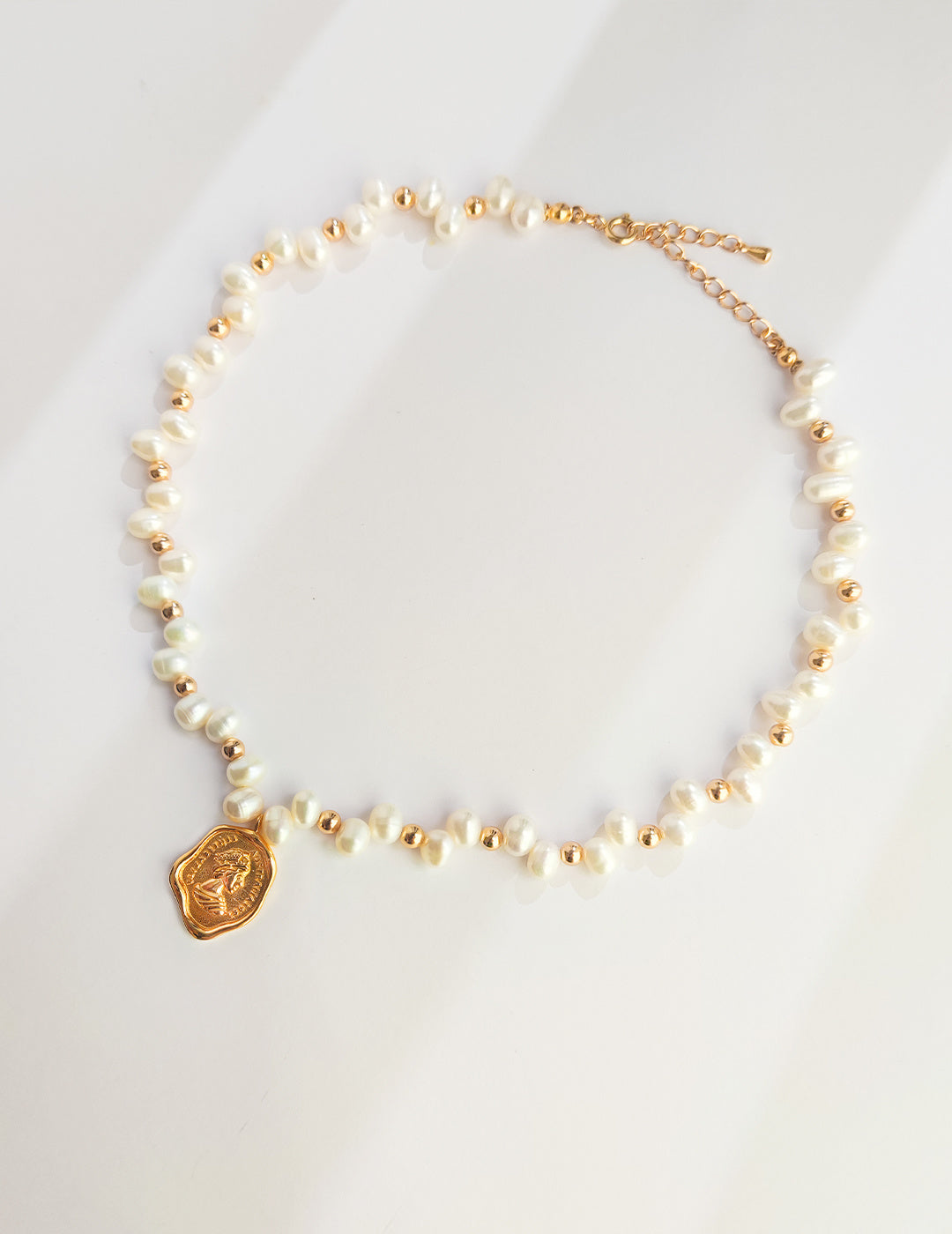 Beautiful gold and white pearl necklace with a charming gold coin pendant, a perfect accessory for elegant occasions.