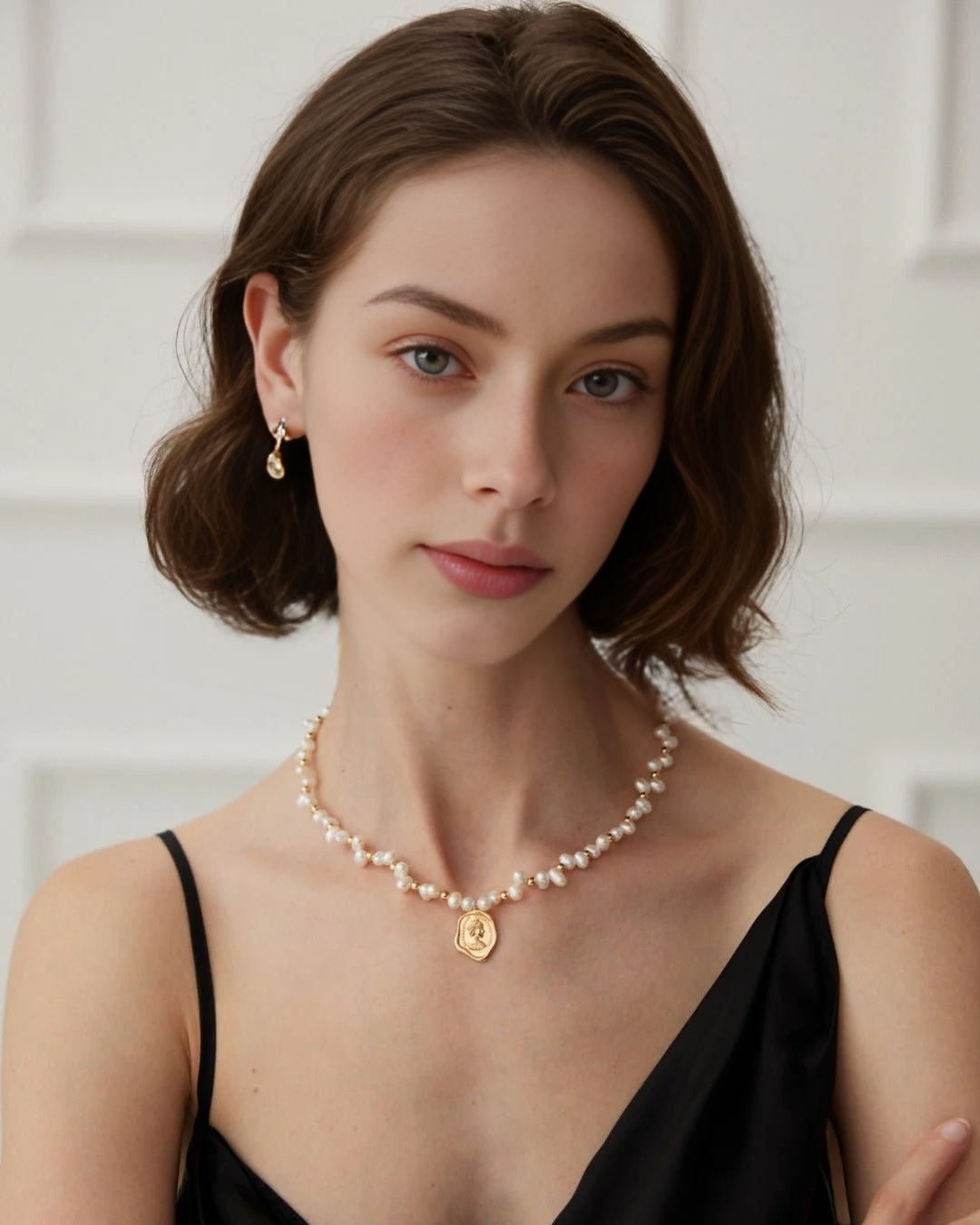 A woman showcasing a beautiful pearl necklace complemented by a gold coin charm.