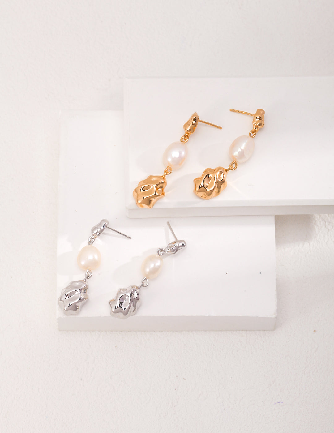 Two pairs of elegant earrings featuring lustrous pearls, one with silver accents and the other with gold accents.