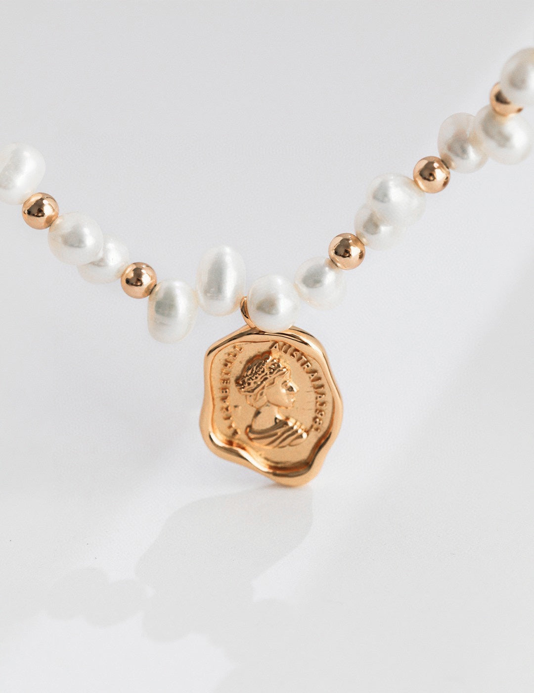 Close-up of the Catarina 18k gold vermeil coin pendant, showing the embossed profile and organic, irregular edge detail.