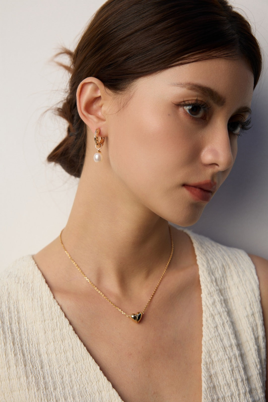 Woman wearing sleek gold pearl hoops, with matching necklace in S925 Silver, by Mezuille.