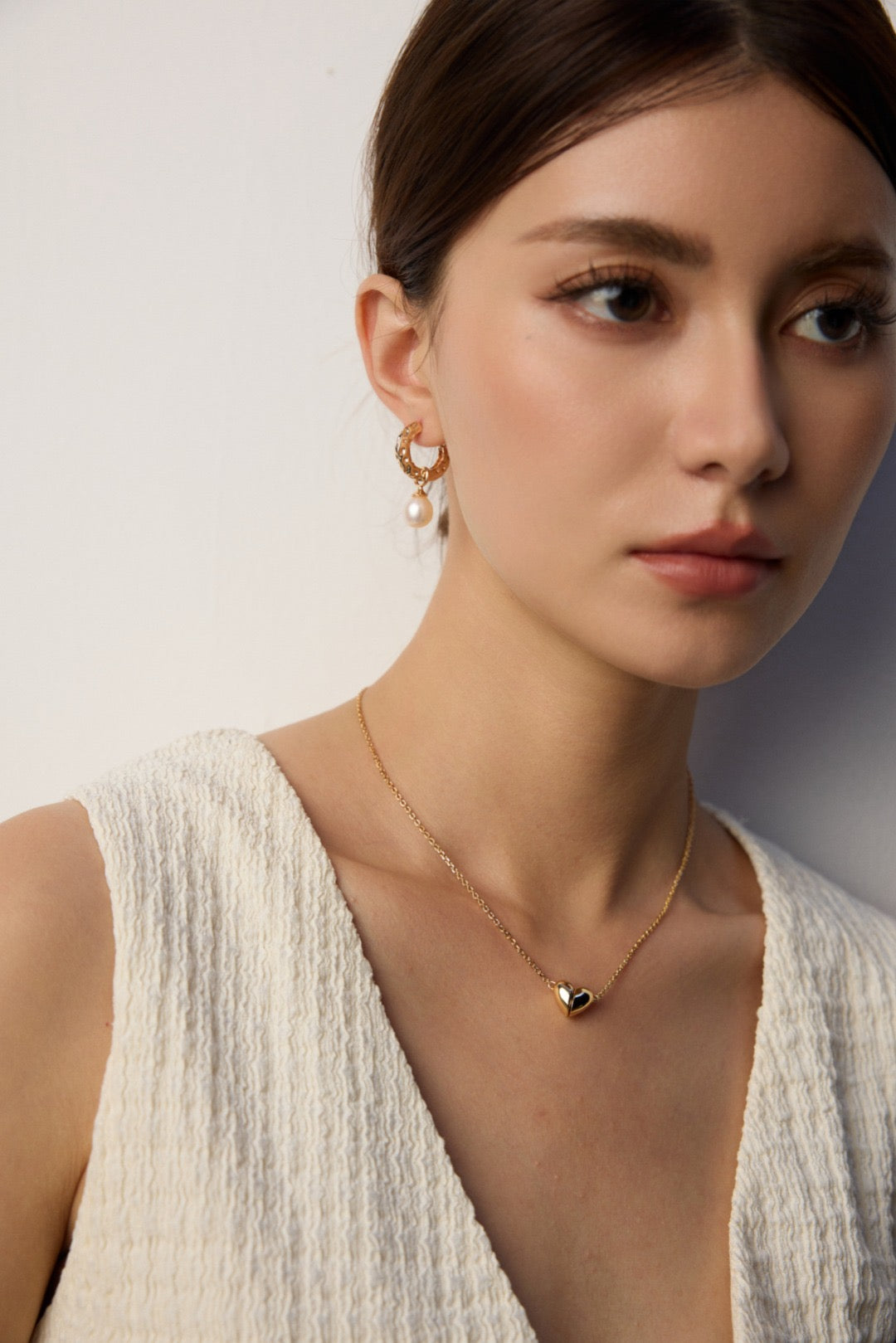 Model wearing elegant gold pearl hoops and pendant necklace by Mezuille.