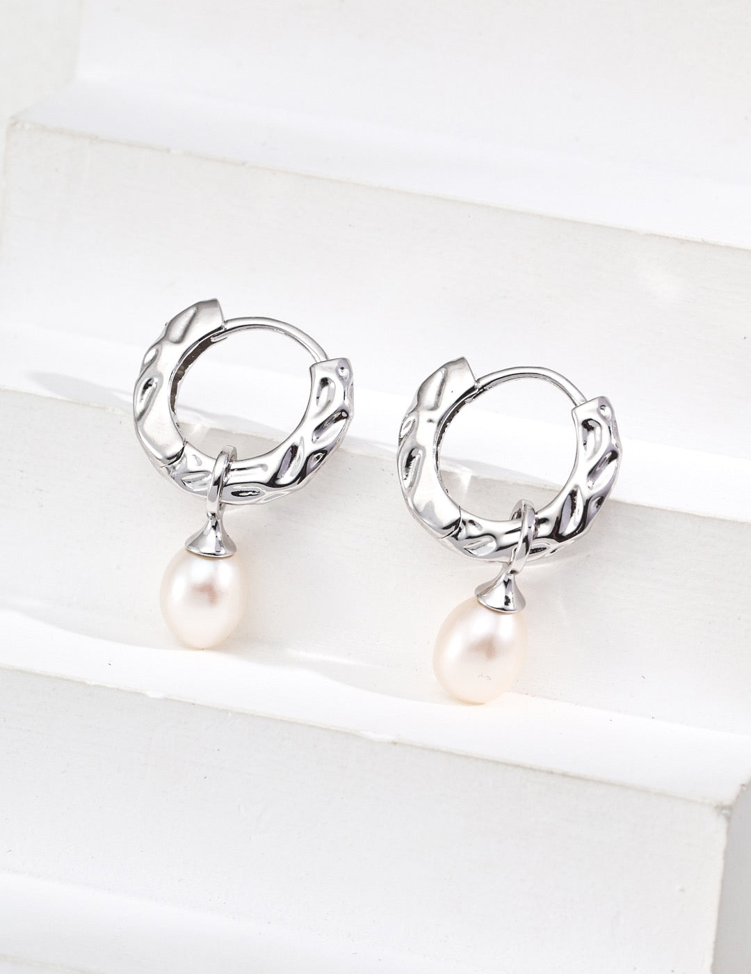 Close-up of silver Mezuille sleek pearl hoops in S925 Silver.