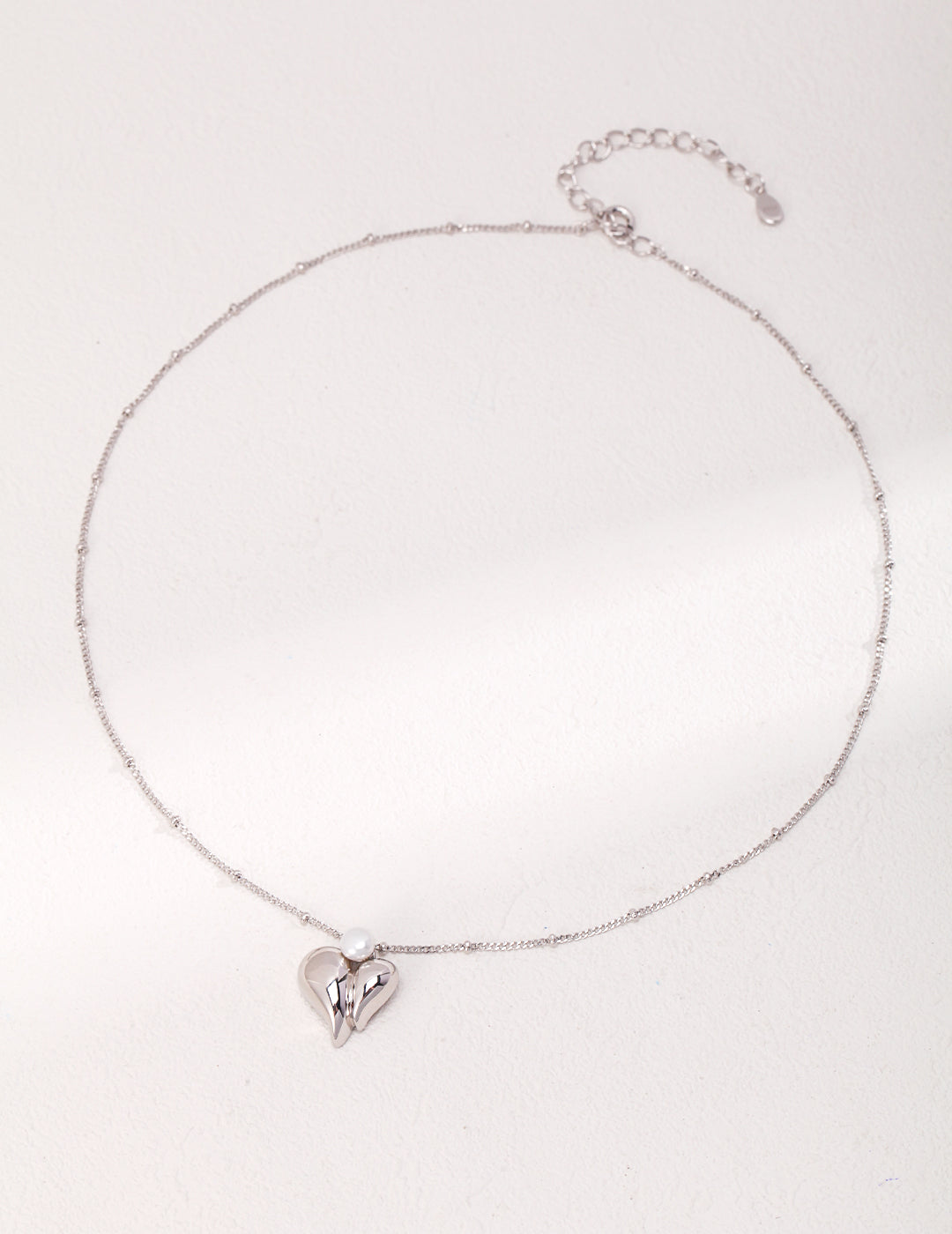 A silver heart necklace with a delicate charm.