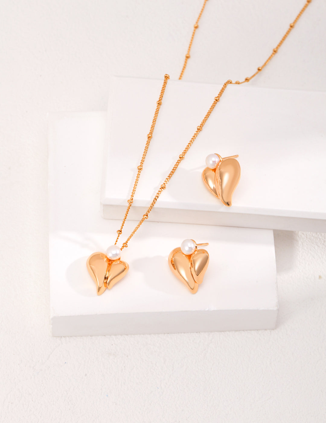 A gold plated heart necklace with matching earrings.