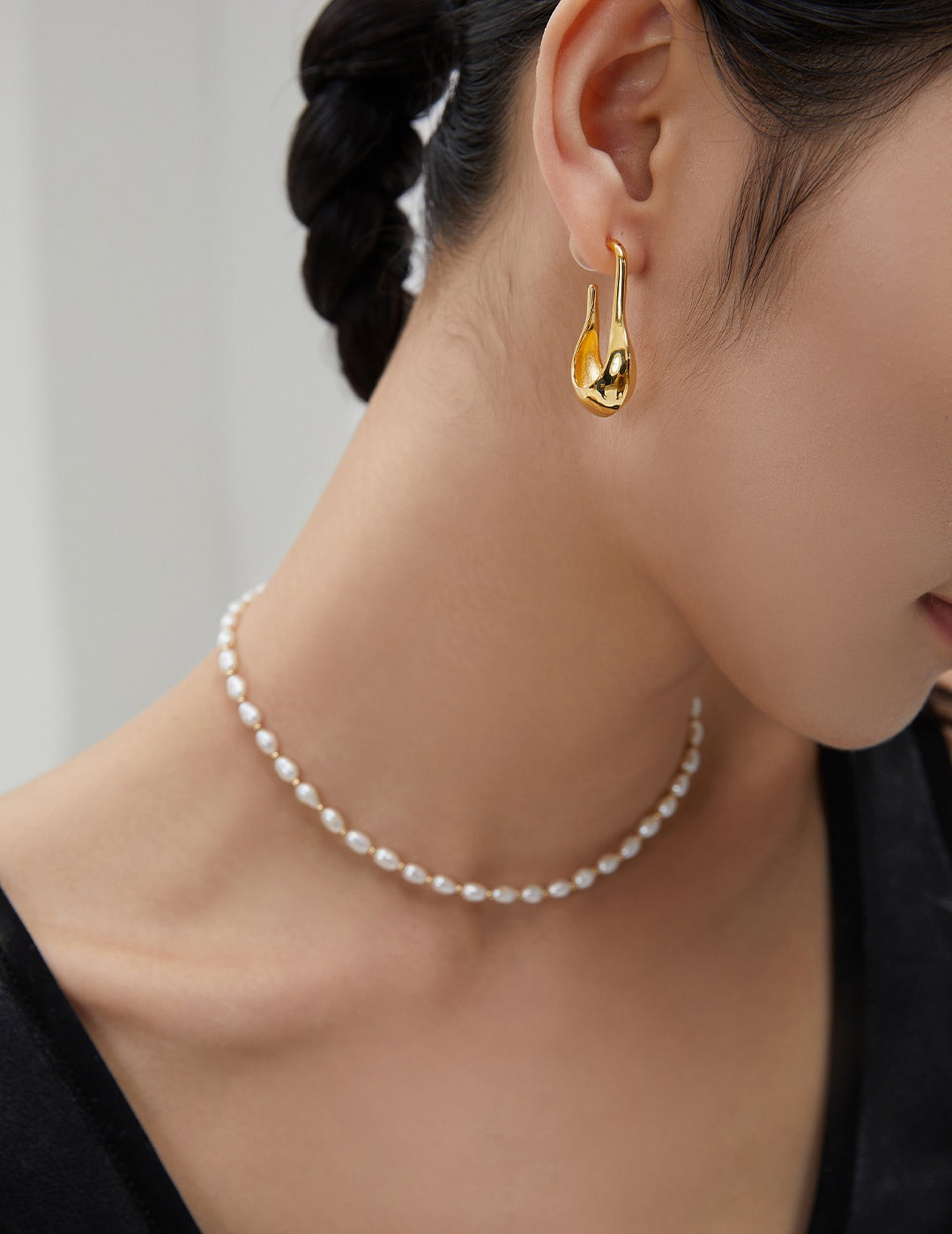 A woman wearing a gold-plated necklace adorned with pearls, adding elegance and sophistication to her look.