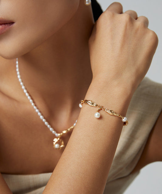 A woman showcasing a gold bracelet and a pearl necklace, embodying elegance and refined fashion in her accessories.