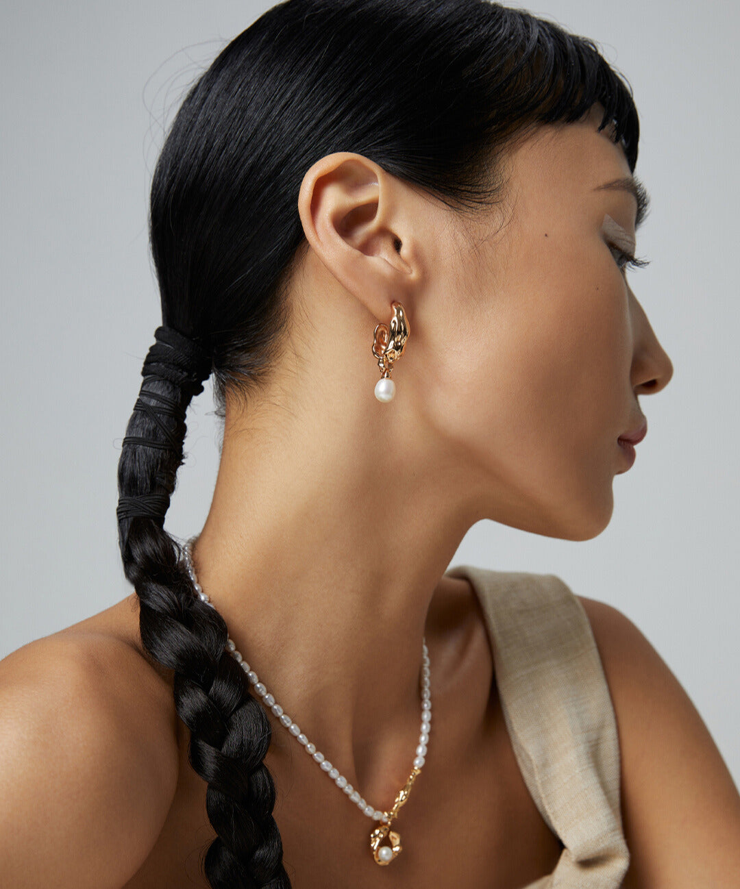 Woman with braid wearing pearl necklace.