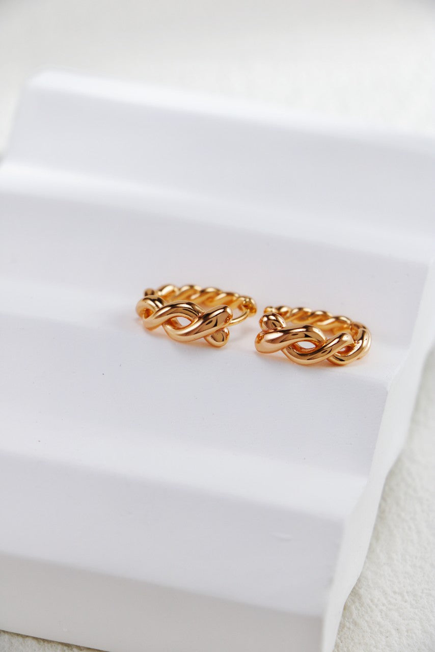 A pair of 18k gold vermeil braided hoop earrings from Mezuille on a white background.
