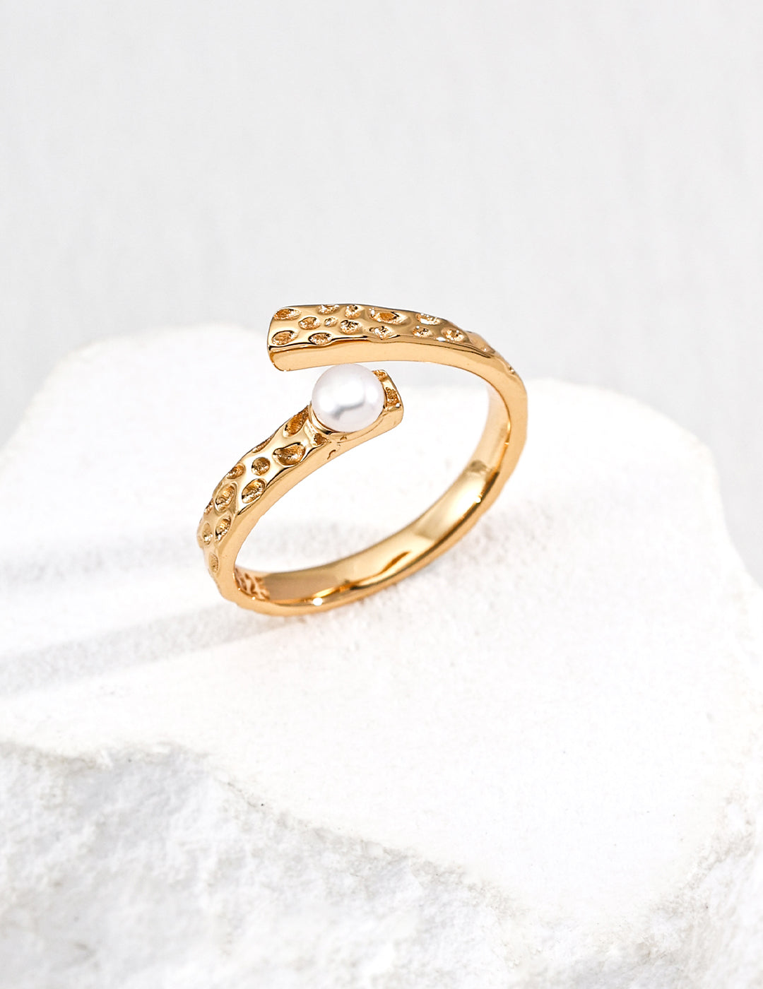 Gold open ring from Mezuille with a delicate pearl, placed on white background